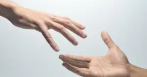 One hand reaching out to another, symbolizing the struggle to connect and bridge emotional distance in relationships.