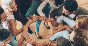 A group of people standing together with arms linked, symbolizing connection, community, and mutual support.