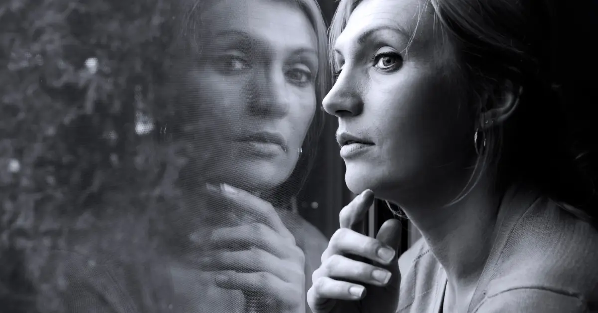 A woman gazing out of a window, symbolizing introspection and self-awareness as she reflects on her behaviors and emotions.