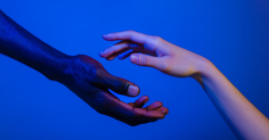 A hand reaching out to another, symbolizing compassion, curiosity, and a connection over judgment or disconnection.