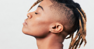 A woman with dreadlocks leaning her head back, eyes closed, embodying strength and self-awareness.